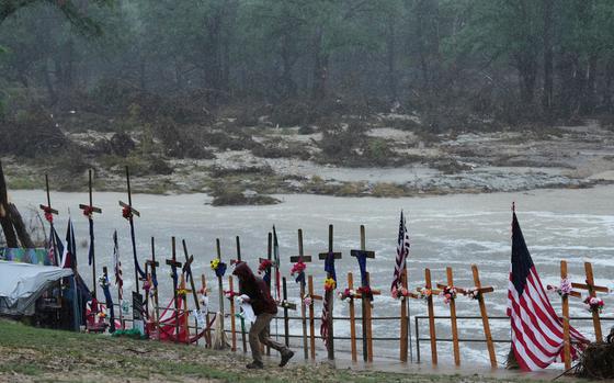 Crosses, many with flowers attached, plus flags line the river.