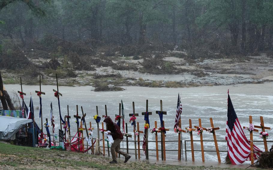 Crosses, many with flowers attached, plus flags line the river.