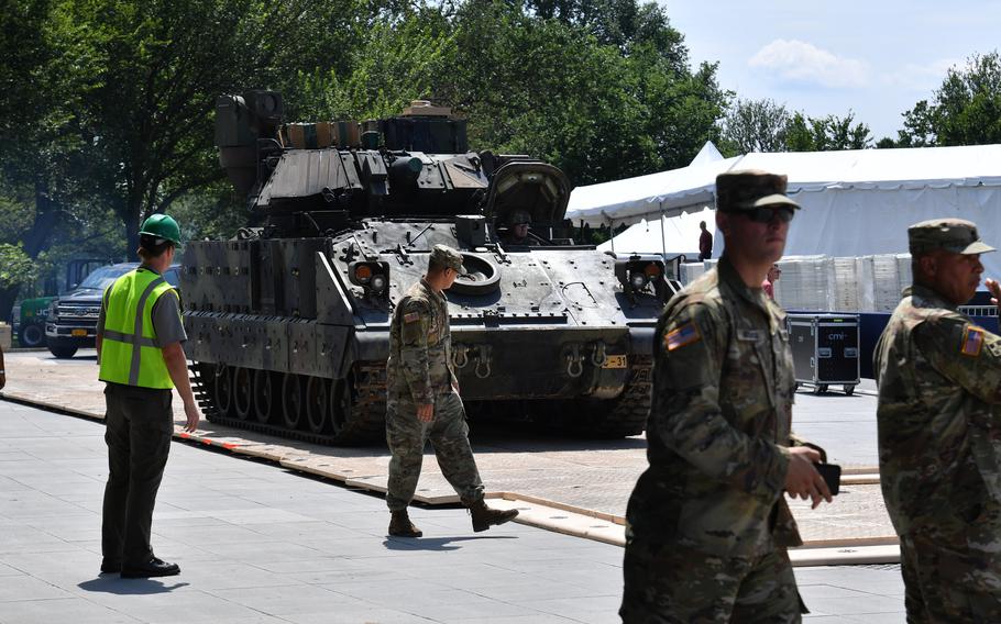 Troops walk past the military vehicle.