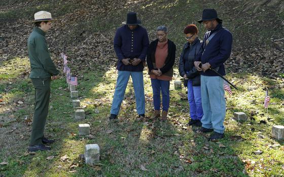 Vicksburg National Military Park Chief of Interpretation Brendan Wilson, left, conducts a ceremony of remembrance with Thelma Sims Dukes, center, Sara Sims, second from right, and two Civil War reenactors at the burial site of 13 soldiers on Feb. 14, 2024, at Vicksburg National Cemetery. The flags were placed at the graves of Black soldiers killed in an 1864 massacre at Ross Landing, Arkansas, who were buried as unknowns but have recently been identified.