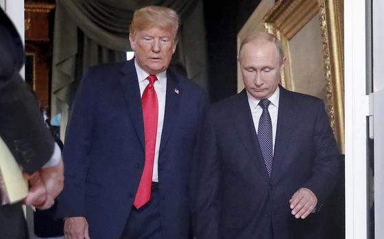 Donald Trump and Vladimir Putin, both wearing dark suits, walk next to each other through an ornate doorway in a government building.