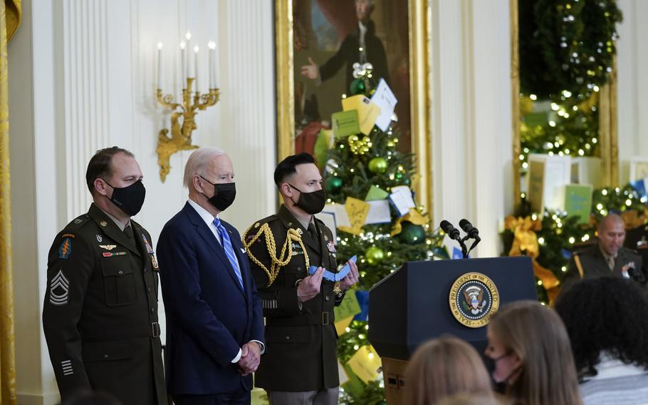 President Joe Biden stands to present the Medal of Honor to Army Master Sgt. Earl Plumlee, left, for his actions in Afghanistan on Aug. 28, 2013, during an event in the East Room of the White House, Thursday, Dec. 16, 2021, in Washington.