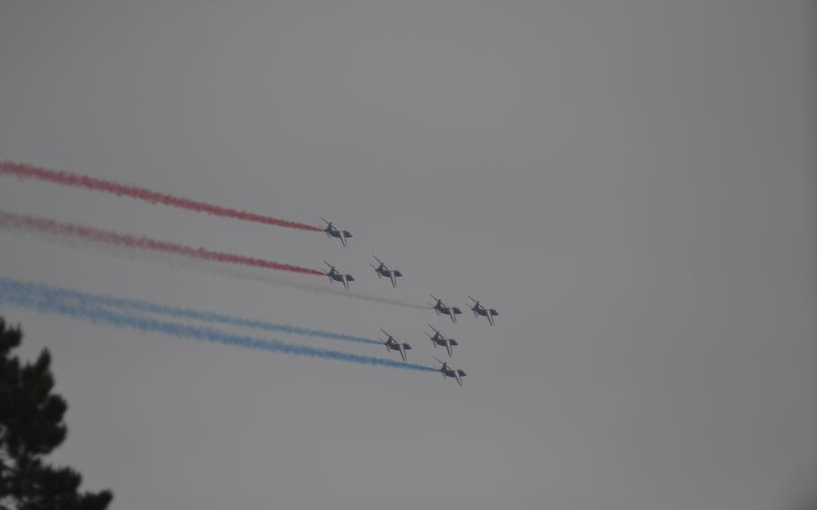 Before Tuesday’s ceremony started, the U.S. and French anthems were played and a group of military aircraft performed a flyover above the cemetery, leaving contrails of red, white and blue — the national colors of France and the United States.