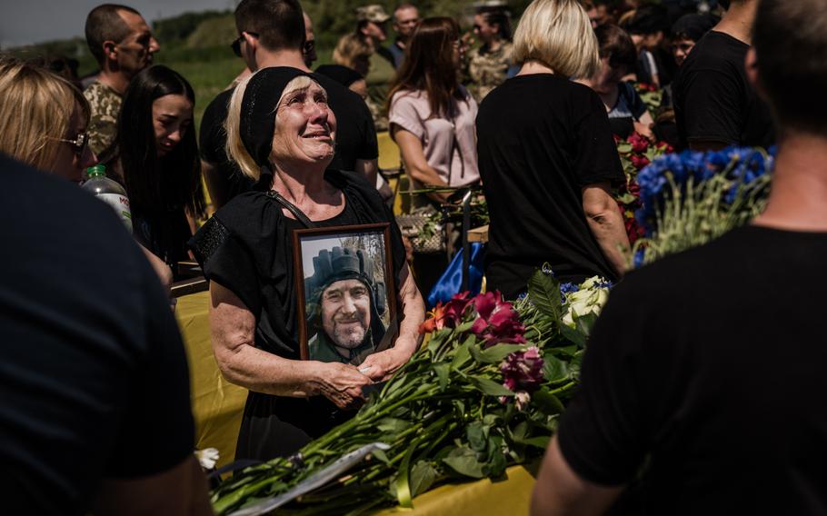 Yaroslava Sushko holds a photo of her son, Serhii V. Sushko, during a funeral for 27 Ukrainian service members who died fighting the Russians, in Dnipro, Ukraine, on June 3. 