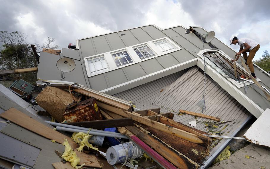 Jeremy Hodges climbs up the side of his family's destroyed storage unit in the aftermath of Hurricane Ida, Monday, Aug. 30, 2021, in Houma, La. 