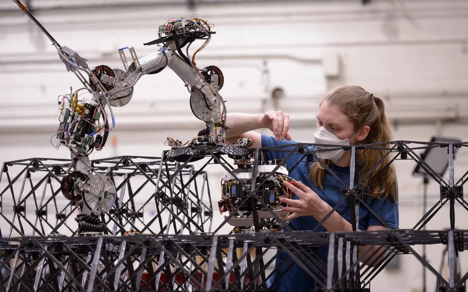 Research engineer Christine Gregg inspects a Mobile Metamaterial Internal Co-Integrator (MMIC-I) builder robot. These simple robots are part of a hardware and software system NASA researchers are developing to autonomously build and maintain high-performance large space structures comprised of building blocks. MMIC-I works by climbing though the interior space of building blocks and bolting them to the rest of the structure during a build or unbolting during disassembly.