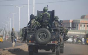 A modified pickup truck carrying soldiers with machine guns and rifles drives down a street.