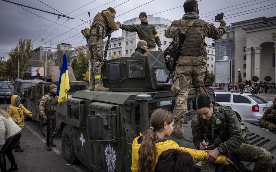 Soldiers met residents and wrote messages on Ukrainian flags in Kherson’s central square,  Nov. 16, 2022. The city is celebrating liberation but many people are in need of food and medicine. 