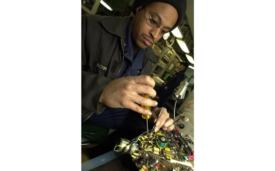 Petty Officer 2nd Class Kenneth Bower works on a video unit for an F-14 Tomcat in the ship’s avionics lab on Monday, April 15, 2002.