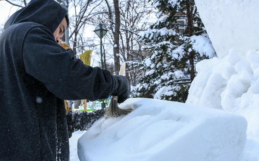Petty Officer 1st Class Godwin Balderas removes snow from the Navy's ice sculpture at the Sapporo Snow Festival in Hokkaido, Japan, Feb. 2, 2023.