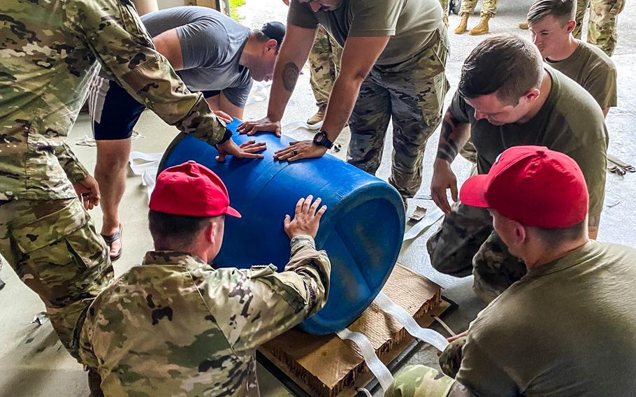 Service members at Andersen Air Force Base, Guam, build an apparatus for dropping medical supplies to a critically injured soldier aboard a vessel at sea, July 25, 2021.