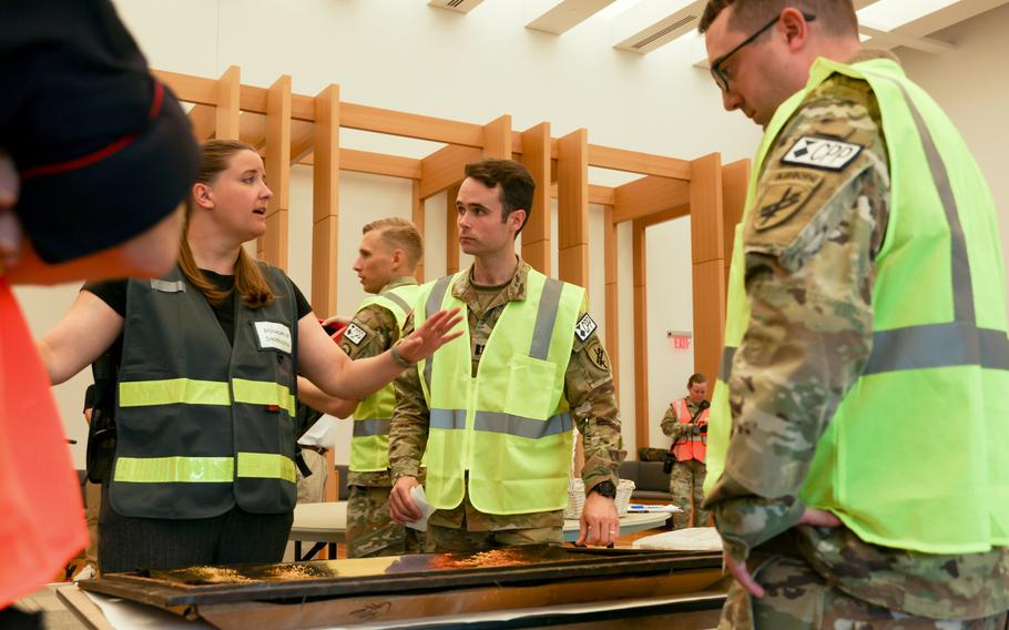 Melissa Weissert, left, playing a frantic collections manager, discusses the evacuation of cultural objects with Capt. Hayden Bassett, center, one of 21 participants of a training exercise conducted by the Smithsonian Cultural Recovery Initiative at the National Museum of the United States Army in Fort Belvoir, Va., on Aug. 10. 