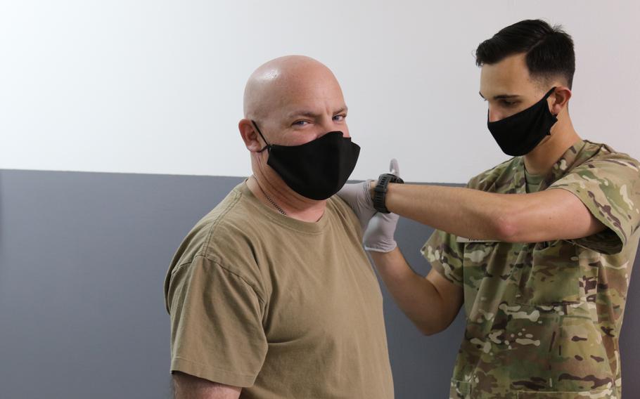 Army Sgt. Maj. Guy Miller, aviation maintenance specialist with the 28th Expeditionary Combat Aviation Brigade, receives a coronavirus vaccine from Sgt. Kenneth Hesler, a combat medic with the 156th Infantry Brigade Combat Team, at a medical clinic at Camp Buehring in Kuwait on March 13, 2021. 