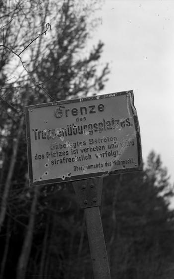 A vertical, black and white photo of a sign post in German.