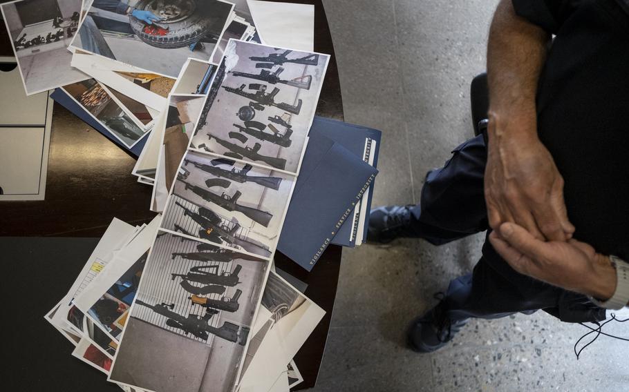 Printed pictures of guns are spread out on a table