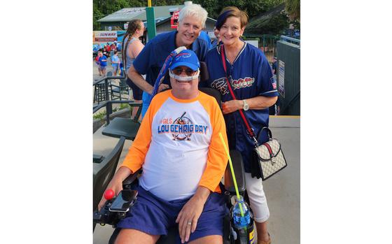 One person in a wheelchair with two others standing behind him as they pose for a photo.