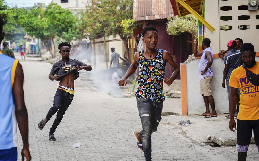 Demonstrators flee tear gas during a violent demonstration that left two people dead in Petitt-Goave, southern Haiti, on August 29, 2022.