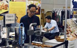 A man watches a machine process pastries.