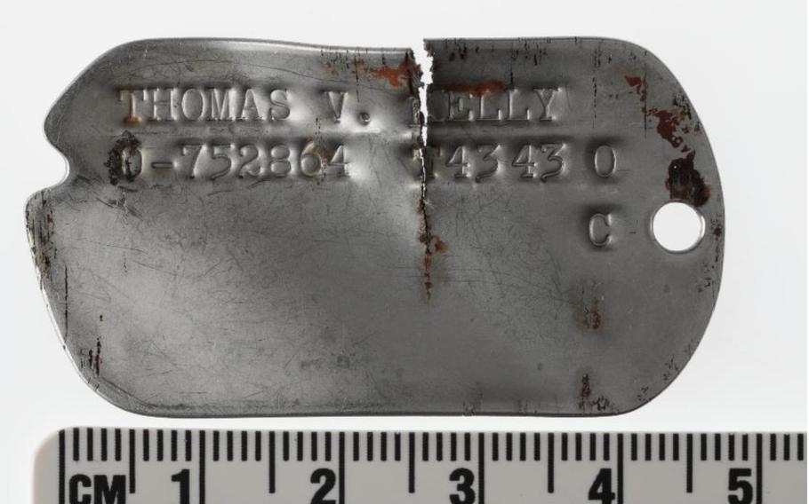 A dog tag on top of a ruler showing the measurement in centimeters.