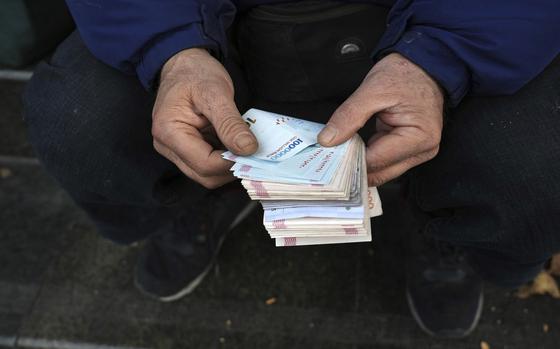 A closeup of two hands holding a wad of cash.