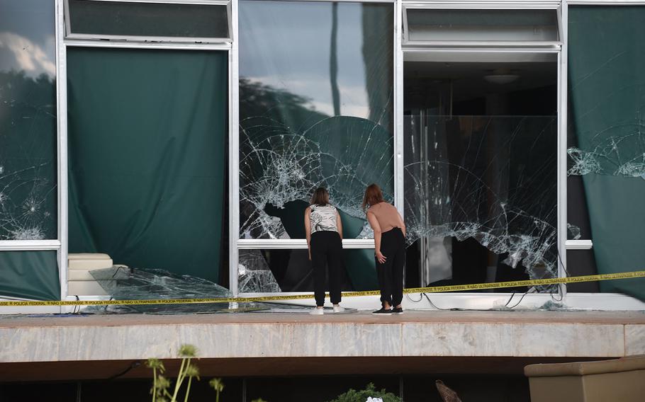 Women look at broken windows of the Supreme Court building in Brasilia on Jan. 10, 2023, two days after thousands of supporters of Brazil’s far-right ex-president Jair Bolsonaro raided federal buildings. 