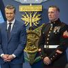 Hegseth in a suit and Meyer in uniform with a representation of the Medal of Honor, reading Valor, in the background.