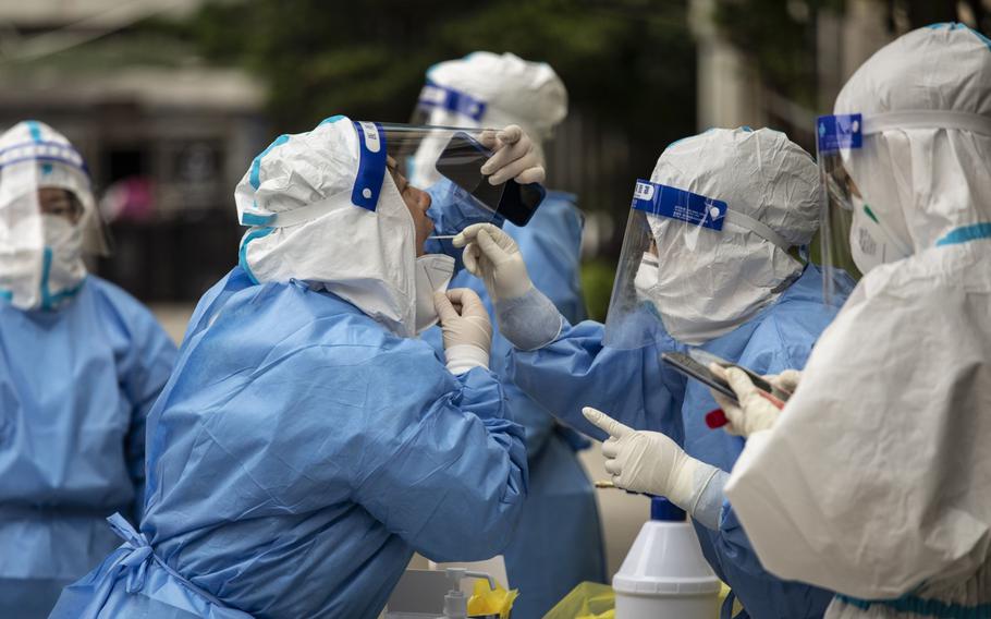 A team of health workers and volunteers in personal protective equipment (PPE) test each other before testing residents at a neighborhood where a suspected flare-up in COVID-19 cases occurred in Shanghai on May 9, 2022. 