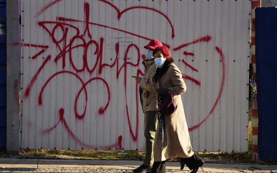 Two women wearing face masks walk along a street in Lisbon, Thursday, Nov. 25, 2021. Portugal is reporting its highest number of new daily COVID-19 infections since July amid a surge in cases across Europe. The Portuguese government is due to announce on Thursday what new pandemic restrictions it is introducing, seven weeks after scrapping almost all of them due to the high vaccination rate.