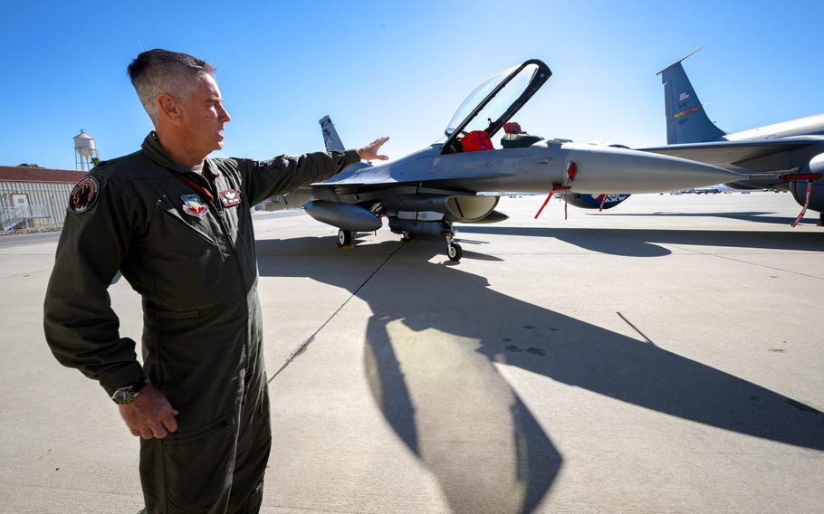 U.S. Air Force Lt. Col Mark Janksy, who pilots the F-16 fighter jet, points to the aircraft after a Super Bowl air defense media briefing at March Air Reserve Base near Riverside on Wednesday, Feb. 9, 2022. Planes at March will join other agencies to protect the skies around SoFi Stadium in Inglewood during the Super Bowl on Sunday, Feb. 13, 2022.