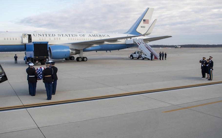 Members of a joint honor guard carry the casket of WWII veteran and former Kansas Sen. Bob Dole toward an Air Force transport plane at Joint Base Andrews, Md., on Friday, Dec. 10, 2021. At right looking on are Chairman of the Joint Chiefs of Staff Gen. Mark Milley, far left, next to Dole's wife Elizabeth, the Doles' daughter Robin, and Army Maj. Garrett Beer.