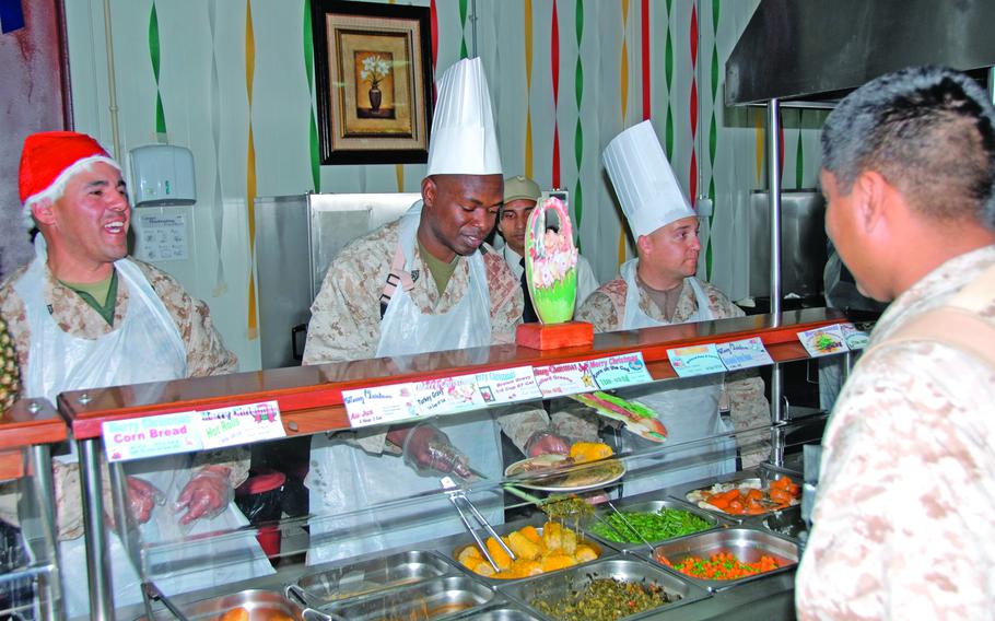 Gunnery Sgt. Robert Ruiz, in the Santa hat, 1st Sgt. Melvin Lewis, center, and Gunnery Sgt. William Neal serve Christmas dinner at the chow hall at Camp Taqaddum, Iraq, Dec. 25, 2006. Noncommissioned officers and officers of the 9th Engineer Support Battalion, from Okinawa, pulled duty at the dining facilities for the holdiay meal. 