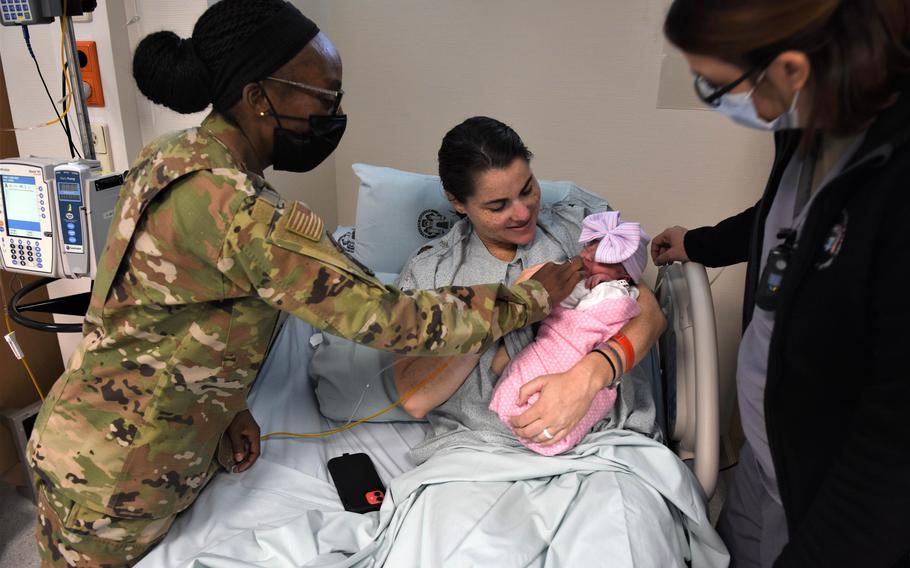 Air Force Capt. Kaitlyn Betts holds her newborn daughter, Raegan McKenna Betts, after giving birth at Landstuhl Regional Medical Center in Germany on July 20, 2022. Air Force Maj. Khimea Sayles, left, and Air Force Capt. Jenny Davis, clinical nurses at LRMC, stand next to her.