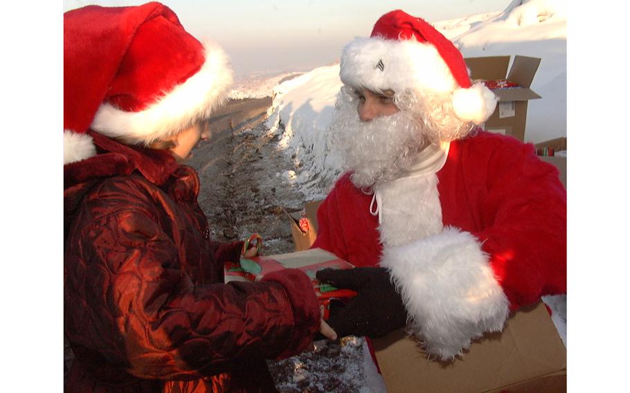 Six-year-old Selma Mesic, a Muslim refugee living near Camp Comanche in Bosnia and Herzegovina, receives Christmas gifts from Santa Claus, also known as Sgt. Troy Patterson of Bravo Company, 2nd Battalion, 224th Aviation Brigade, on Dec. 25, 2001.