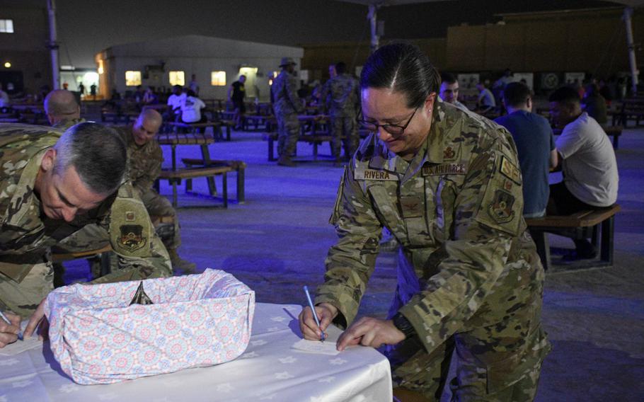 U.S. Air Force Col. Amy Rivera, director of staff at the 379th Air Expeditionary Wing, writes a message to be placed inside a time capsule at a ceremony in Al Udeid Air Base, Qatar, April 22, 2022. The time capsule marked the 20th anniversary of the unit’s reactivation.