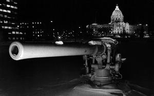 The gun in shadows, with the capitol building lit up in the background.