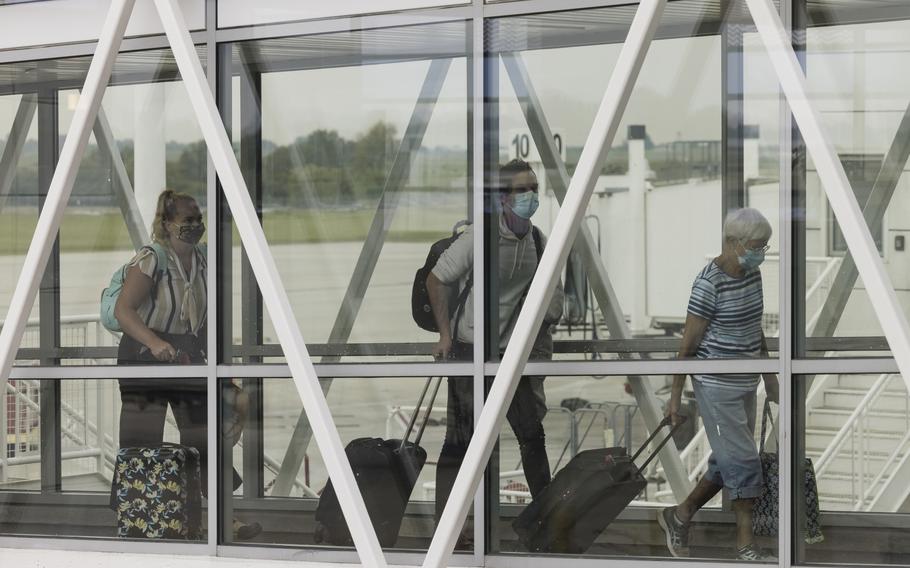 Travelers wearing face masks walk down a jet bridge at Springfield-Branson National Airport in Springfield, Mo., on Aug. 5, 2021. 