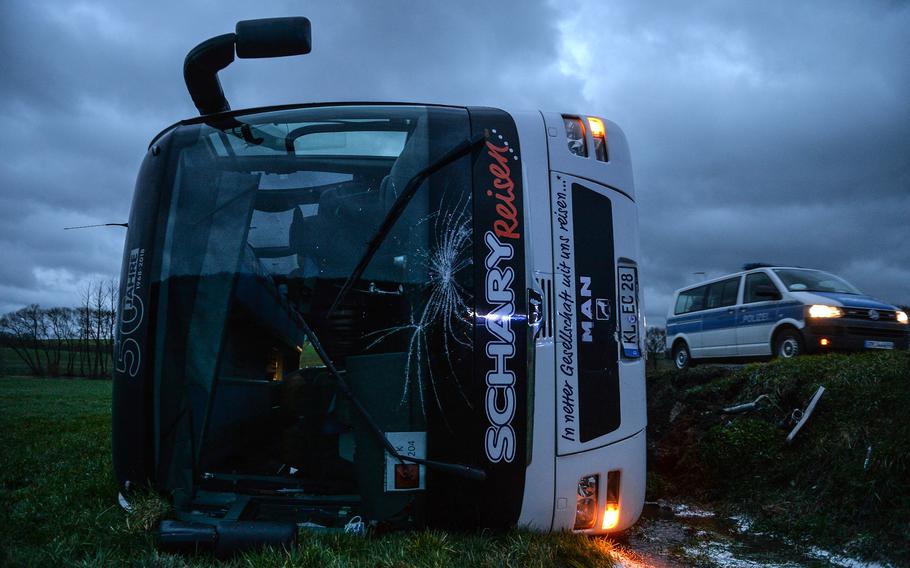 A DODEA school bus lies on the ground after heading off an embankment Friday, March 10, 2023, near Weilerbach, Germany. Sixteen students were on board, and one was taken to Landstuhl Regional Medical Center with minor injuries, authorities at the Weilerbach firehouse said.