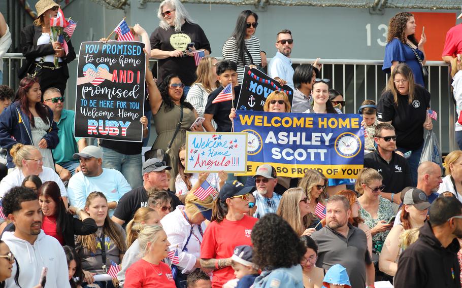A group of people wave American flags and hold banners