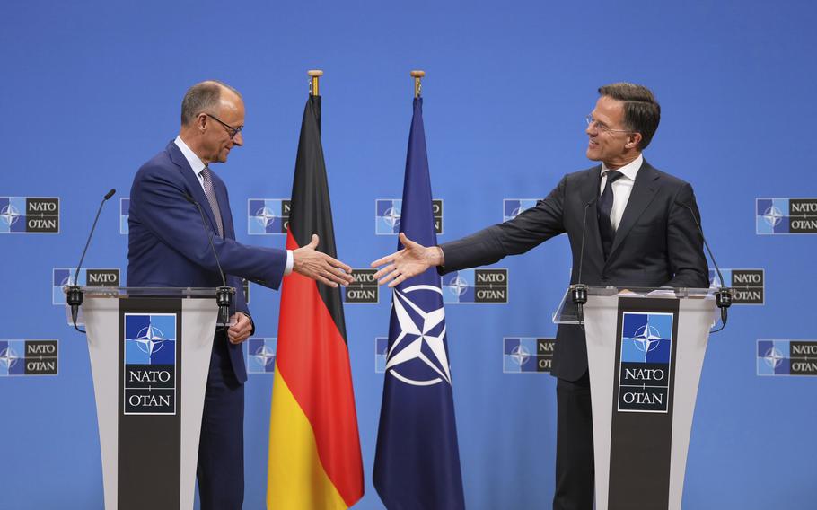 Merz and Rutte, standing at lecterns with the Germany and NATO flags behind then, shake hands.