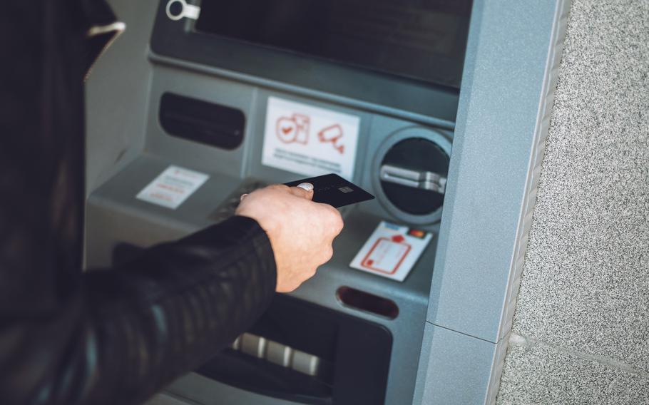 Close-up of female hand with credit card near ATM machine