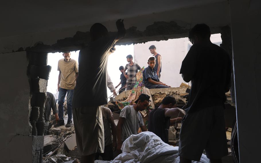 Men walk around the site of an Israeli strike.