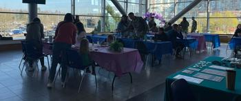 Groups of people gathered at purple table-clothed tables to eat pancakes