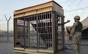 In this June 22, 2004, photo, a detainee in an outdoor solitary confinement cell talks with a military police officer at the Abu Ghraib prison on the outskirts of Baghdad, Iraq. A trial scheduled to begin Monday, April 15, 2024, in U.S. District Court in Alexandria, Va., will be the first time that survivors of Iraq’s Abu Ghraib prison will bring their claims of torture to a U.S. jury. Twenty years earlier, photos of abused prisoners and smiling U.S. soldiers guarding them shocked the world.
