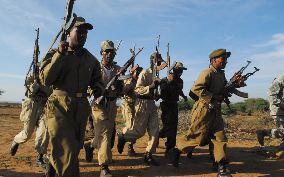 Ethiopian soldiers chant and pump their Kalashnikov rifles following a day of training in the field with U.S. military instructors.