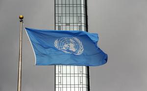 The blue and white U.N. flag obscures part of a skyscraper.
