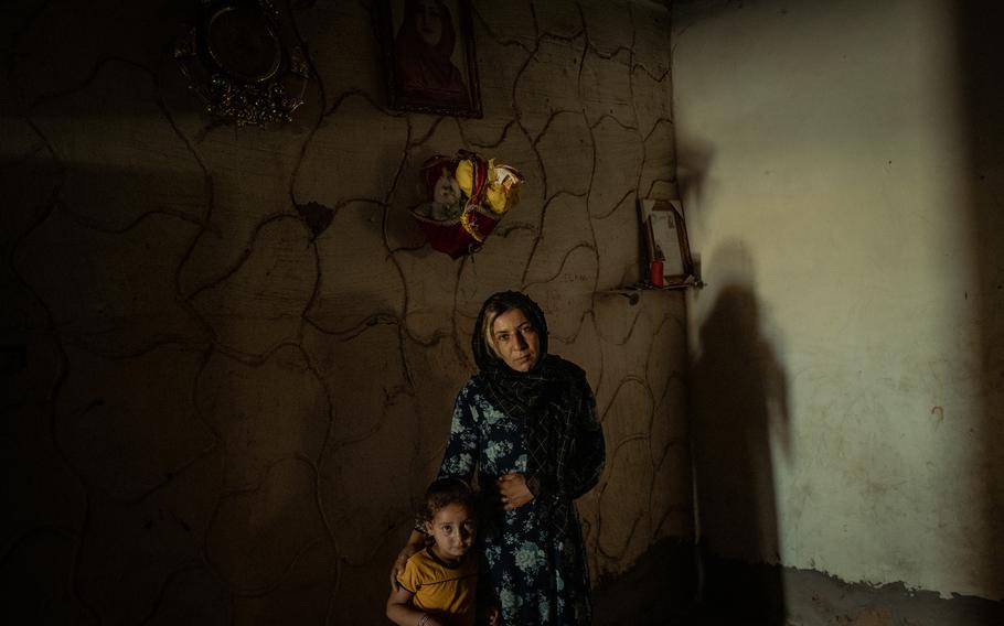 Rusil Latif al-Khadir, 4, and Hiyam Latif al-Khadir, 22, the daughter and sister, respectively, of Hind Latif al-Khadir, stand beneath a portrait of her at their home in Dashisha, close to Syria's border with Iraq. 