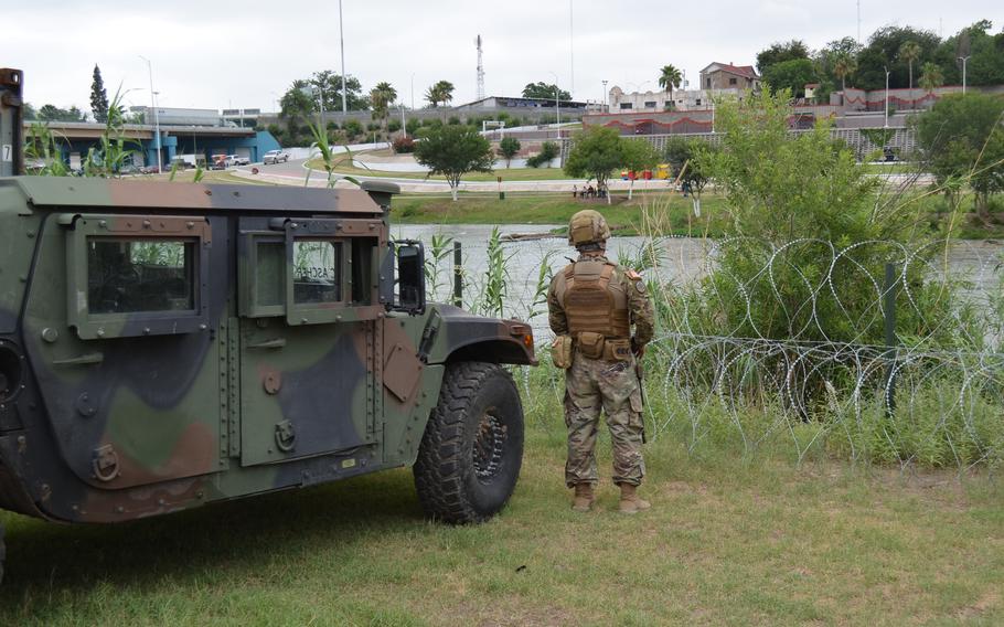 A Texas National Guard soldier looks through a coiled barbed wire barrier into Mexico from Eagle Pass, Texas, on May 23, 2022. 