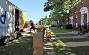 A man uses equipment to move household items into a truck.
