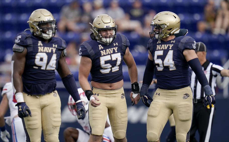Navy linebacker Johnny Hodges, center, reacts with teammates J’arius Warren, left, and Diego Fagot after Hodges deflected a pass from SMU quarterback Tanner Mordecai, during the first half of an NCAA college football game, Saturday, Oct. 9, 2021, in Annapolis, Md.