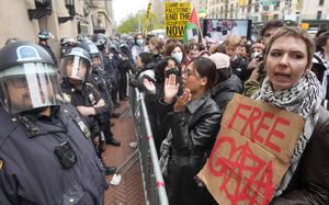 Police in Riot gear stand guard as demonstrators chant slogans outside the Columbia University campus, in New York on April 18, 2024.